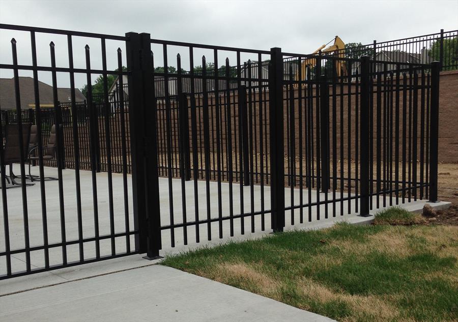 Black ornamental fence installed around a concrete patio